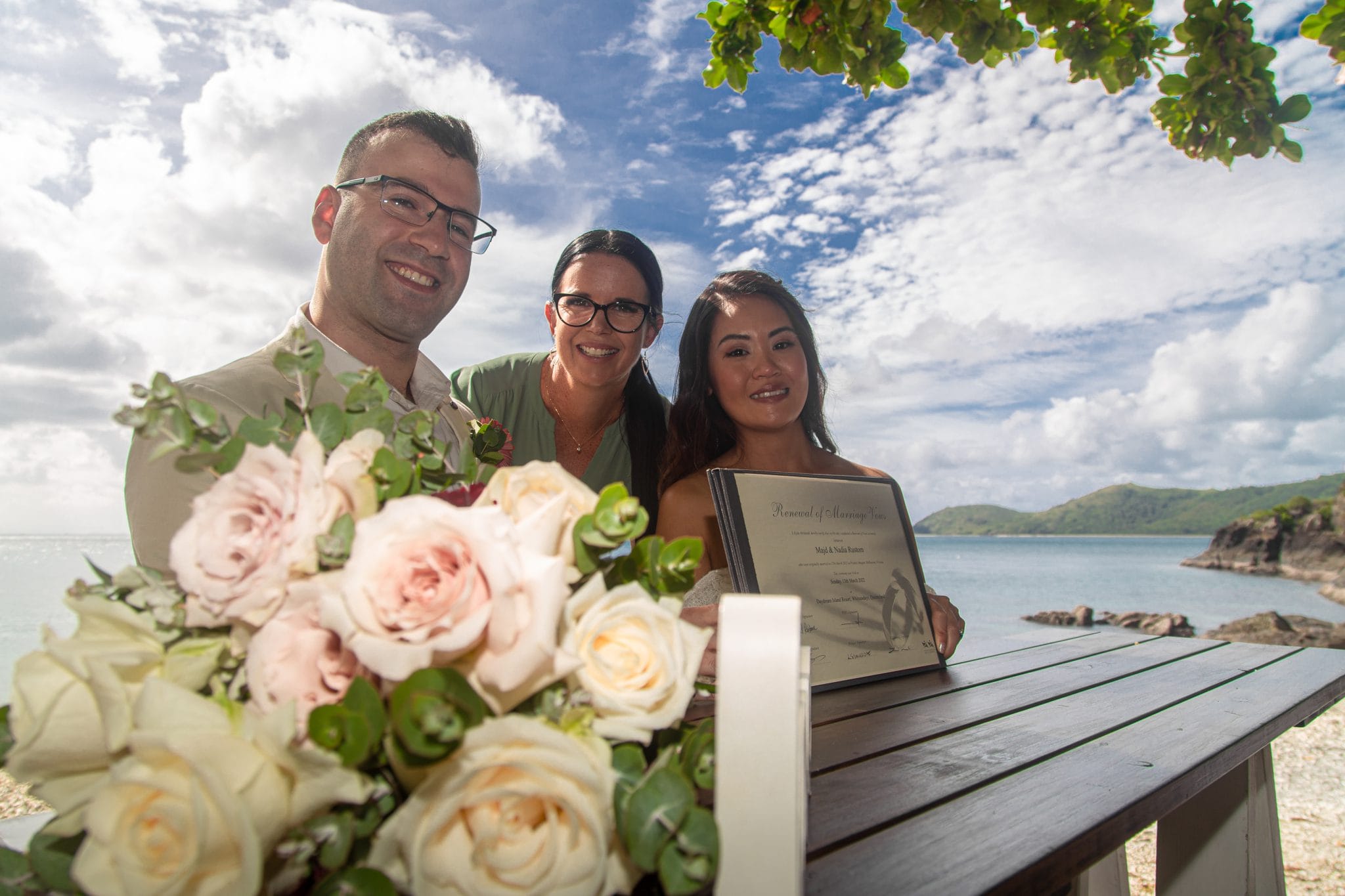 Bride and groom holding marriage certificate by the beach
