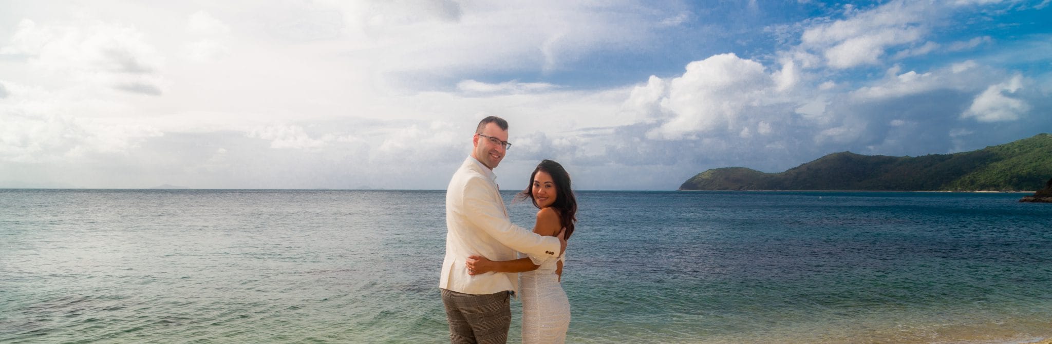 Bride and groom by the beach looking back at the camera