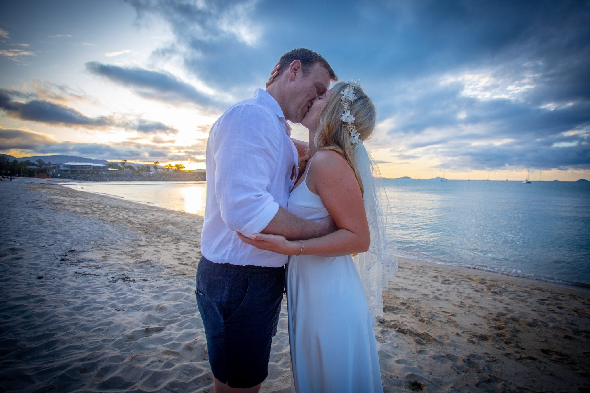 Bride and groom kissing on the beach at sunset