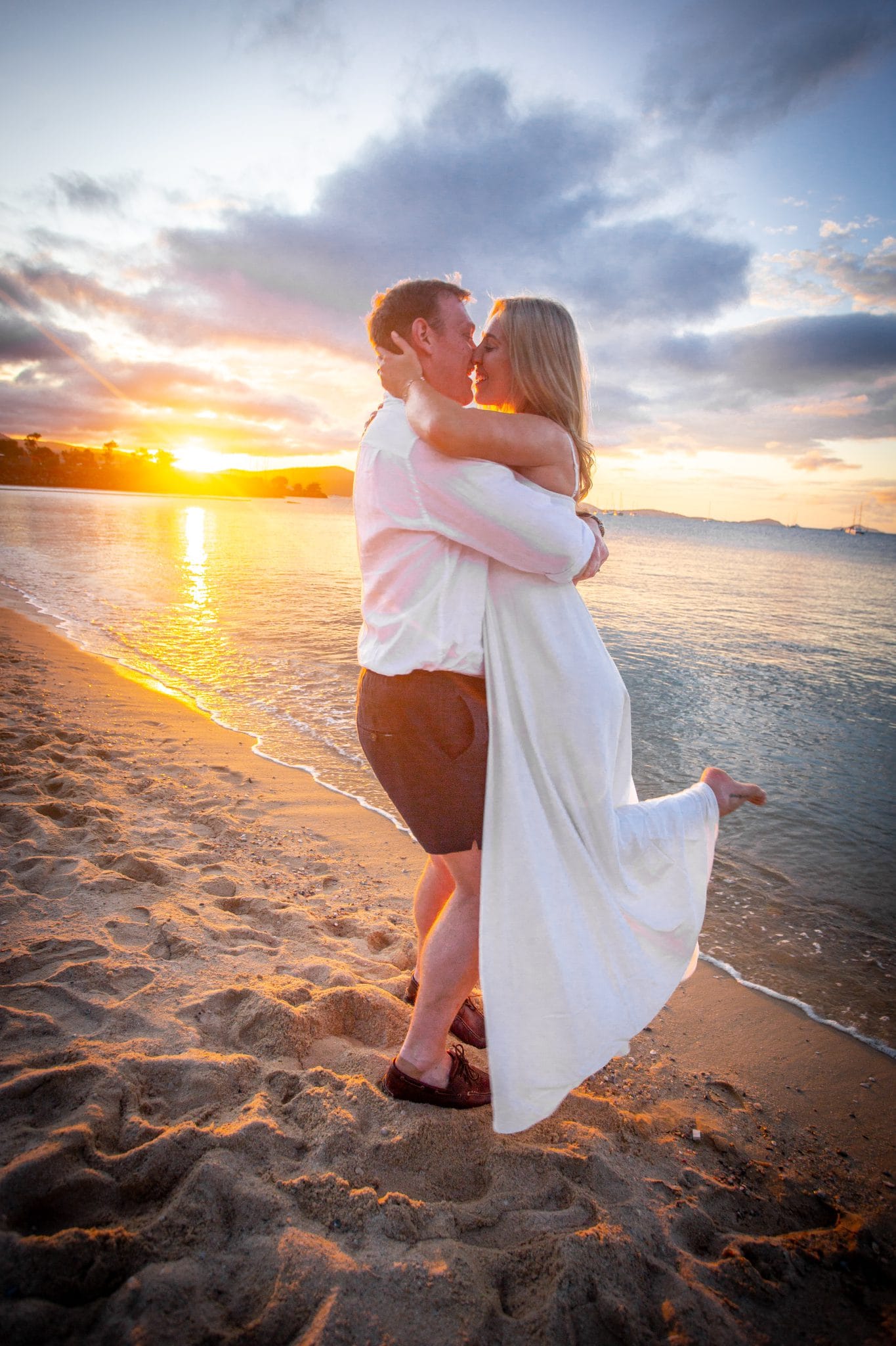Bride and groom kissing on the beach at sunset