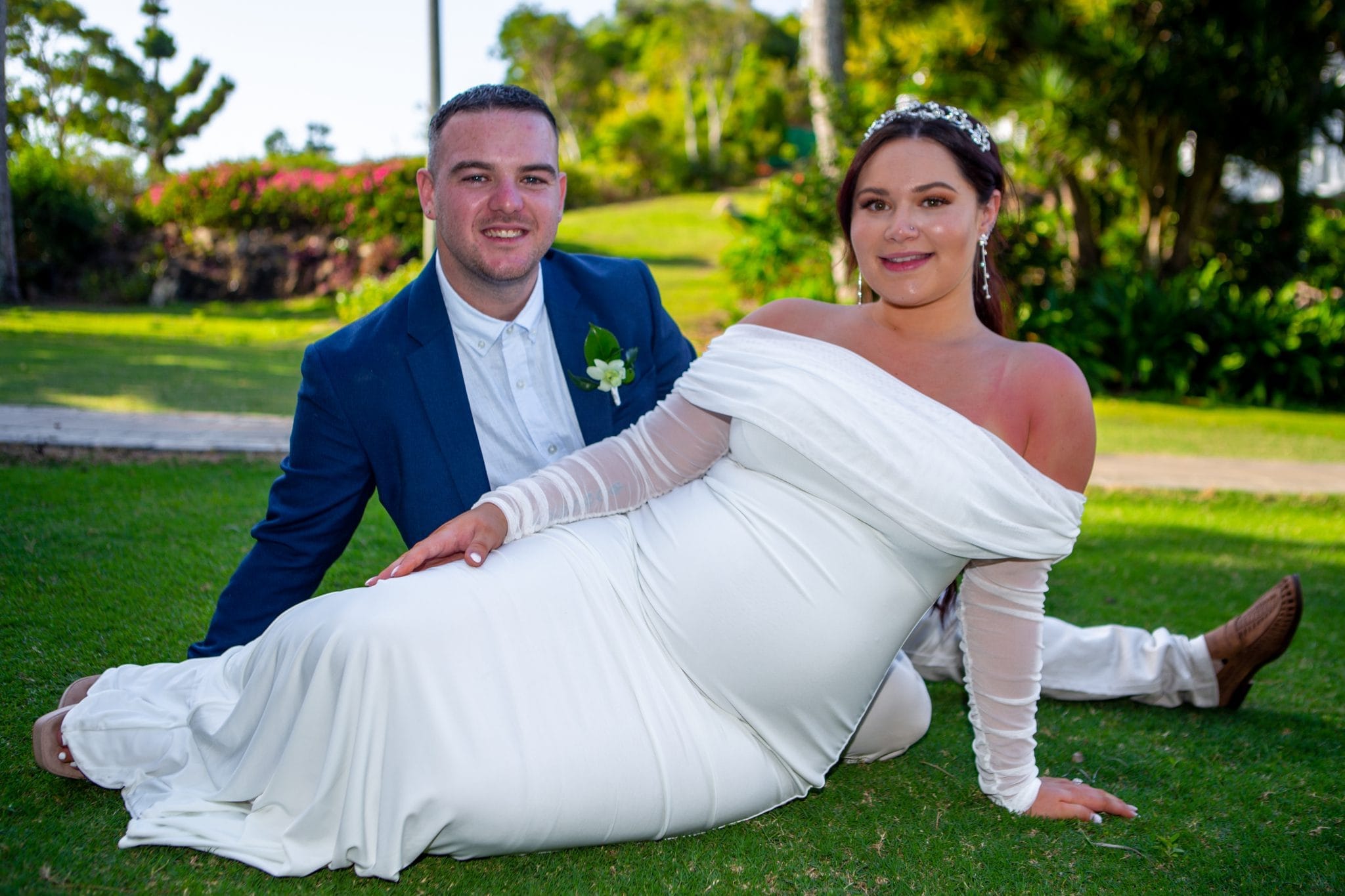 Bride and groom sitting on the grass smiling for a photo