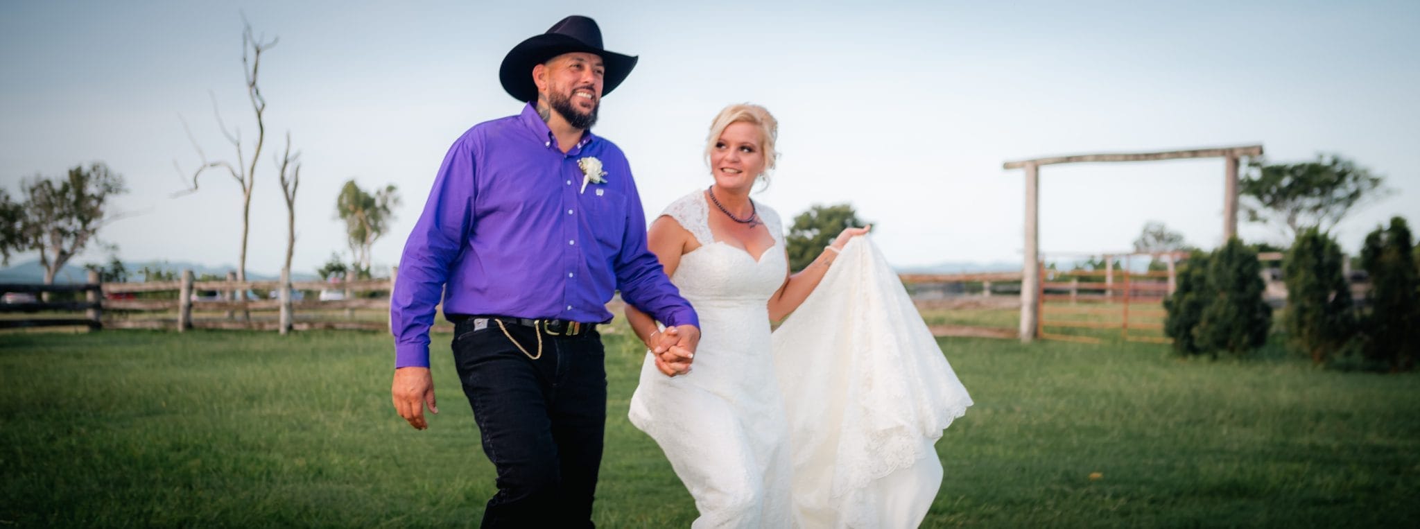 Bride and groom walking together on green grass
