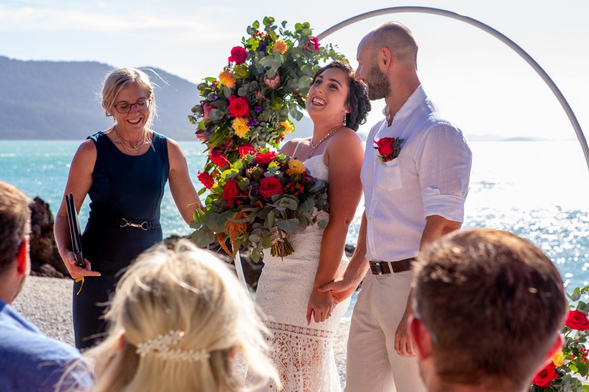 Bride and groom laughing together by the beach