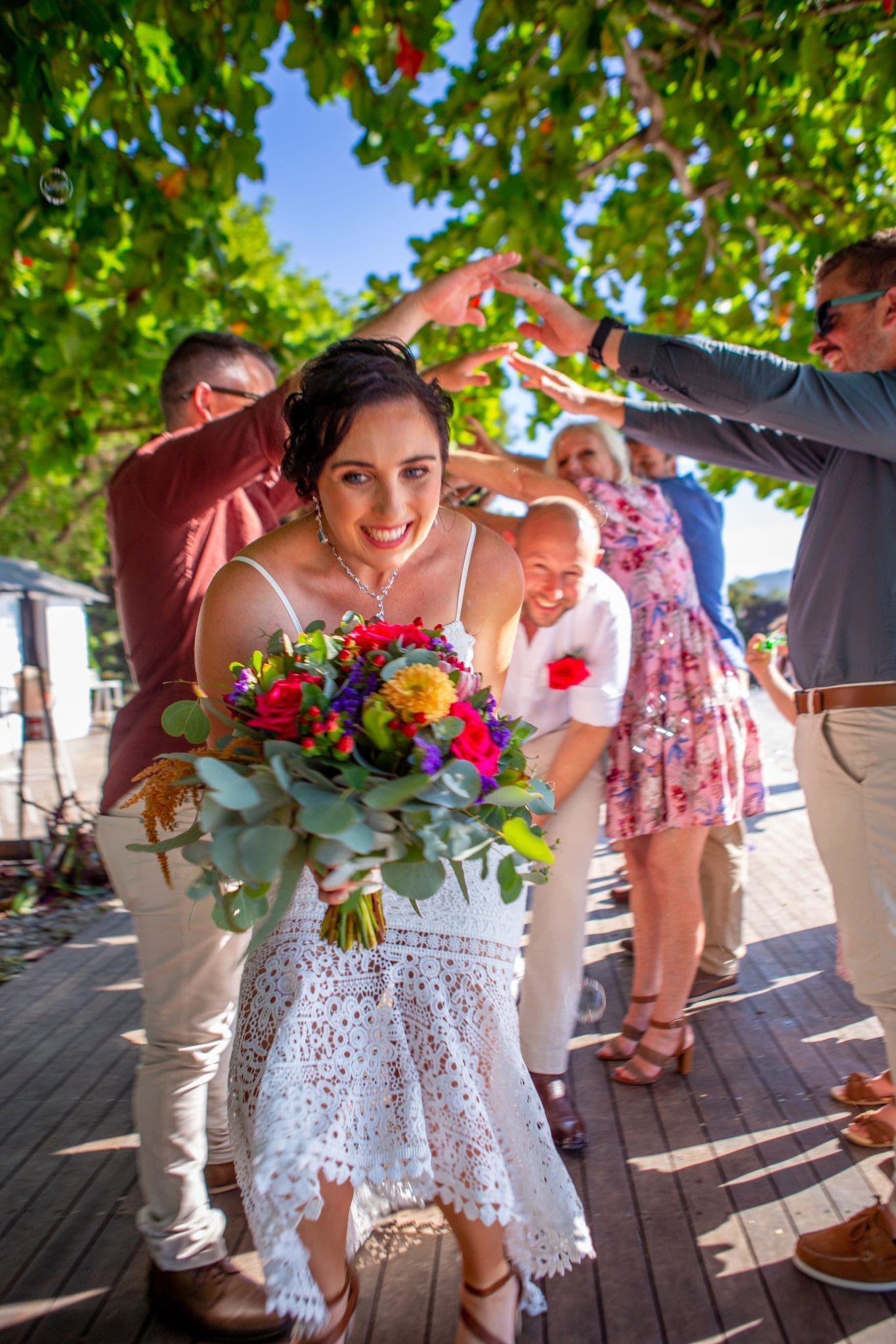 Bride walking under people holding their arms outreached in an arch